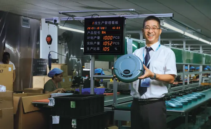 mitarbeiter von der pinduoduo inc betreibt lächelnd einen staubsaugroboter in der Produktion